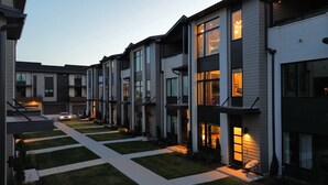 A modern residential building with a central courtyard, featuring a series of connected houses with large windows and a well-maintained lawn.