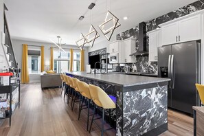 A modern kitchen with a marble island, bar stools, and stainless steel appliances.
