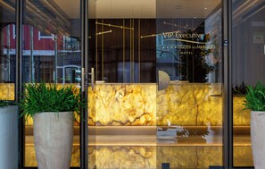 A hotel reception area with a marble counter, glass doors, and potted plants. - VIP Executive Suites do Marques Hotel (Lisbon)