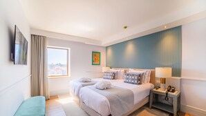 A modern hotel room with a large bed, bedside tables, a flat-screen TV, and a window with curtains. - VIP Executive Suites do Marques Hotel (Lisbon)