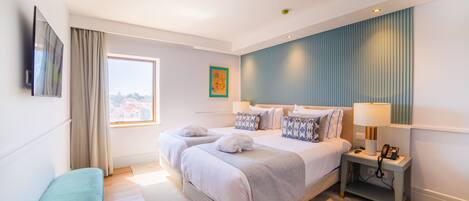A modern hotel room with a large bed, bedside tables, a flat-screen TV, and a window with curtains.