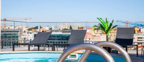 A rooftop pool with lounge chairs and a view of the cityscape.
