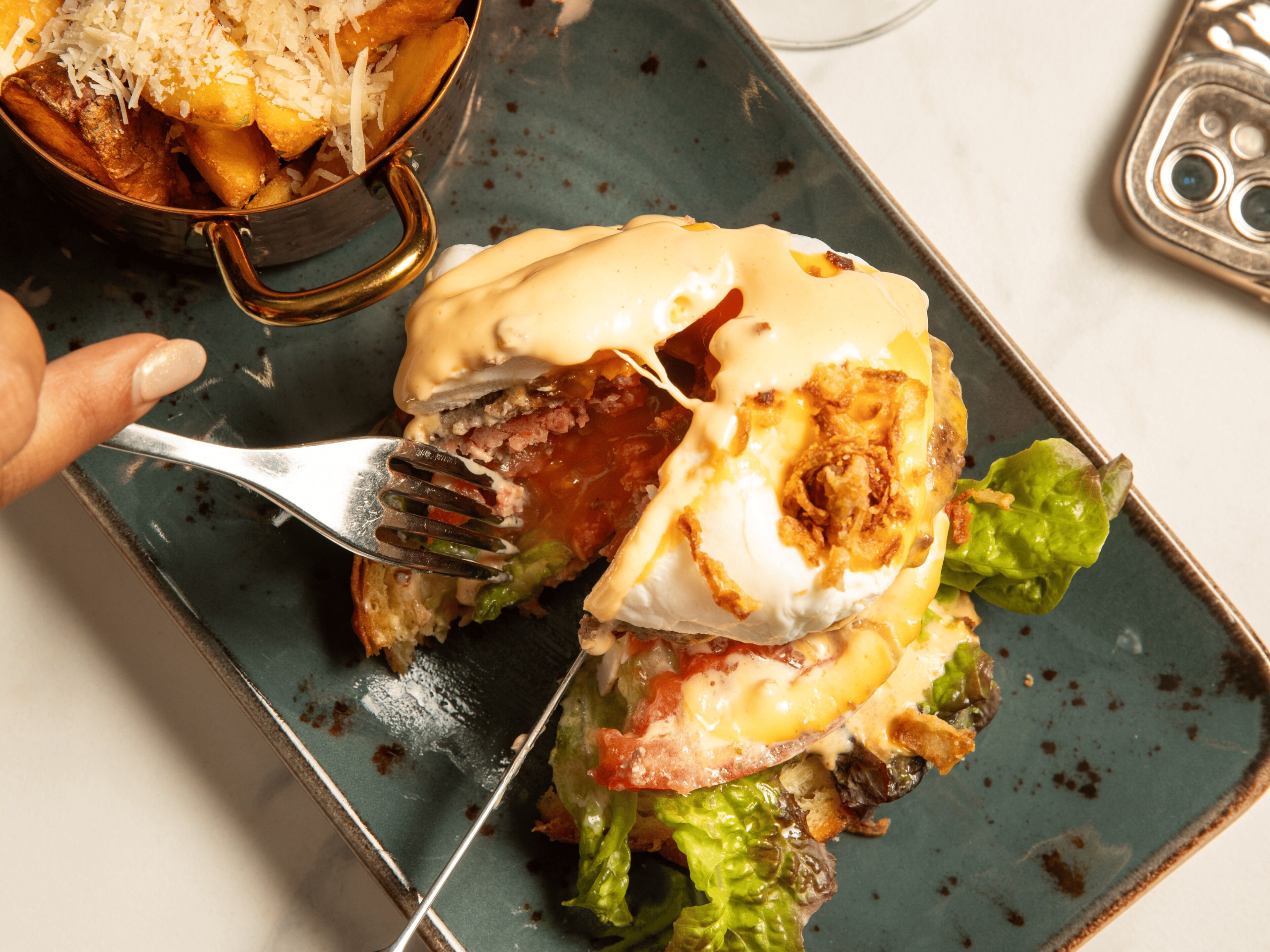 A close-up of a breakfast dish with eggs, bacon, and greens on a plate.