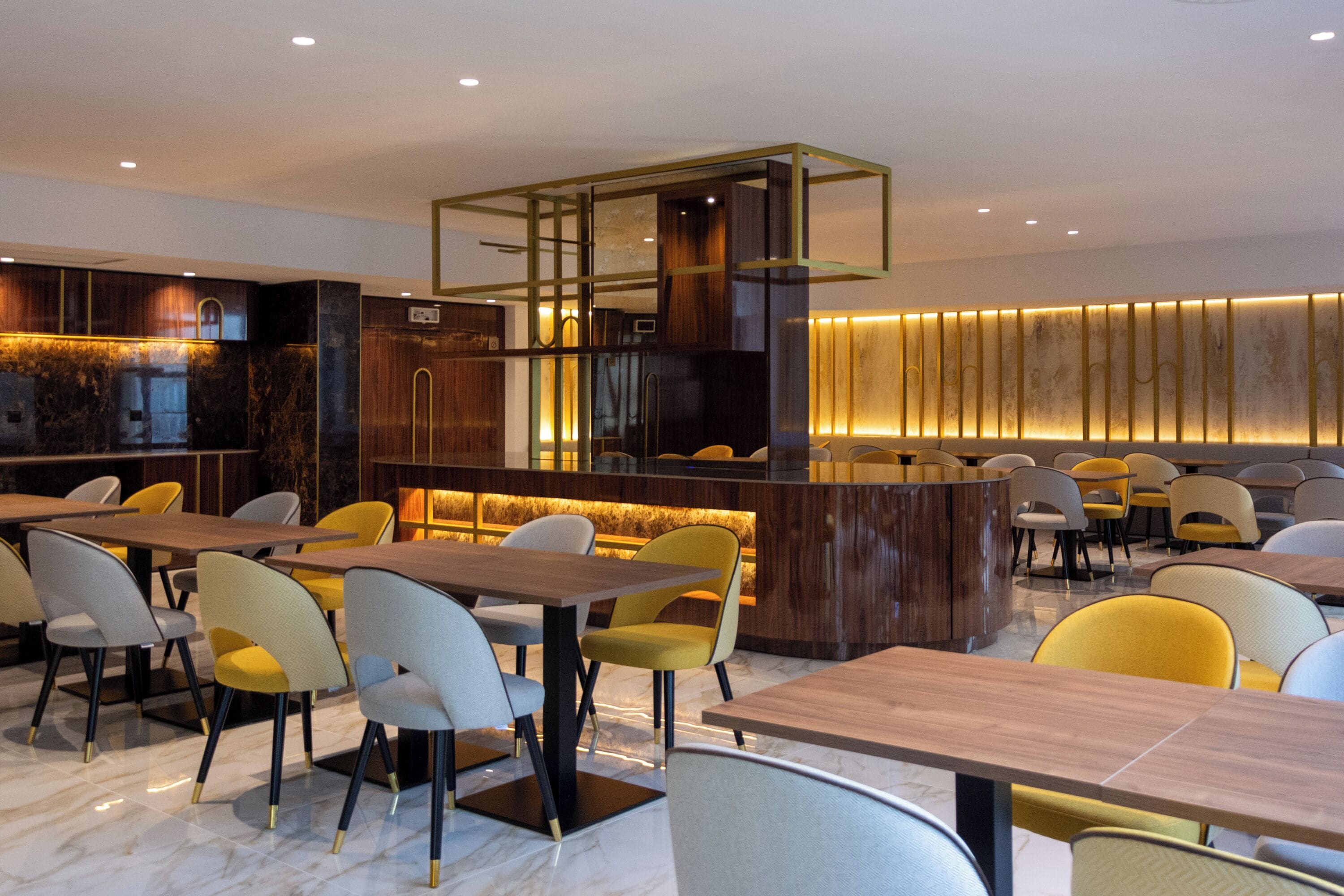 A modern restaurant with wooden tables and chairs, a central bar area, and a marble floor.