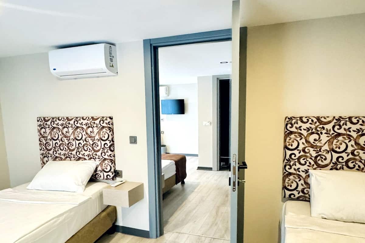 Une chambre d’hôtel avec deux lits, un téléviseur à écran plat et un climatiseur fixé au plafond.