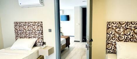 A hotel room with two beds, a flat-screen TV, and a ceiling-mounted air conditioner.