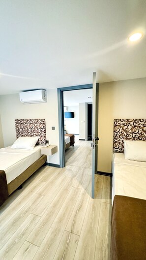 Een hotelkamer met twee bedden, een flatscreen televisie en een aan het plafond gemonteerde airconditioning.