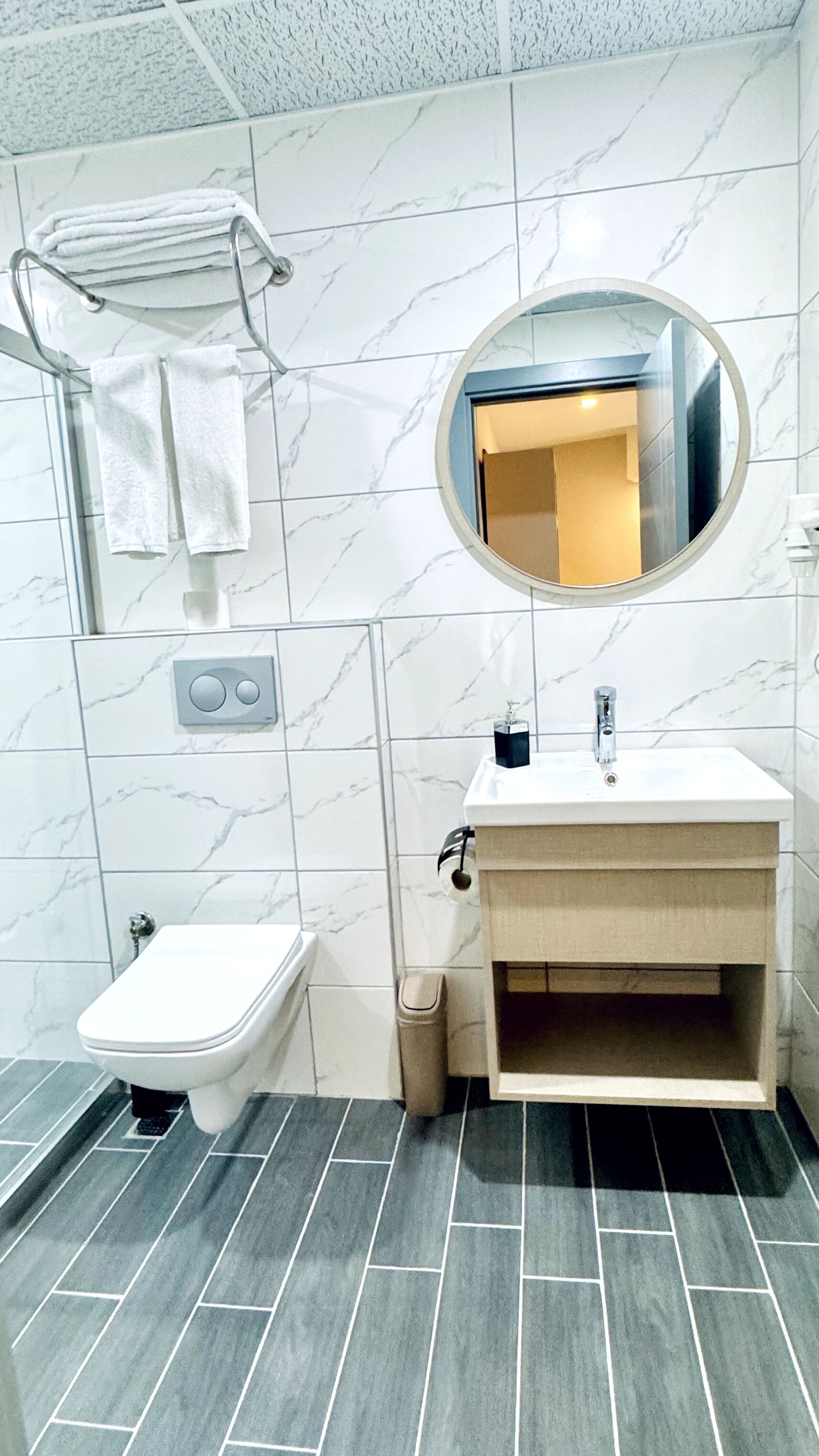 A bathroom with a toilet, sink, and mirror.