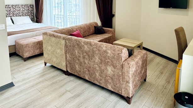 Quarto de hotel moderno com sofá, cama, televisão e vista para a cidade.