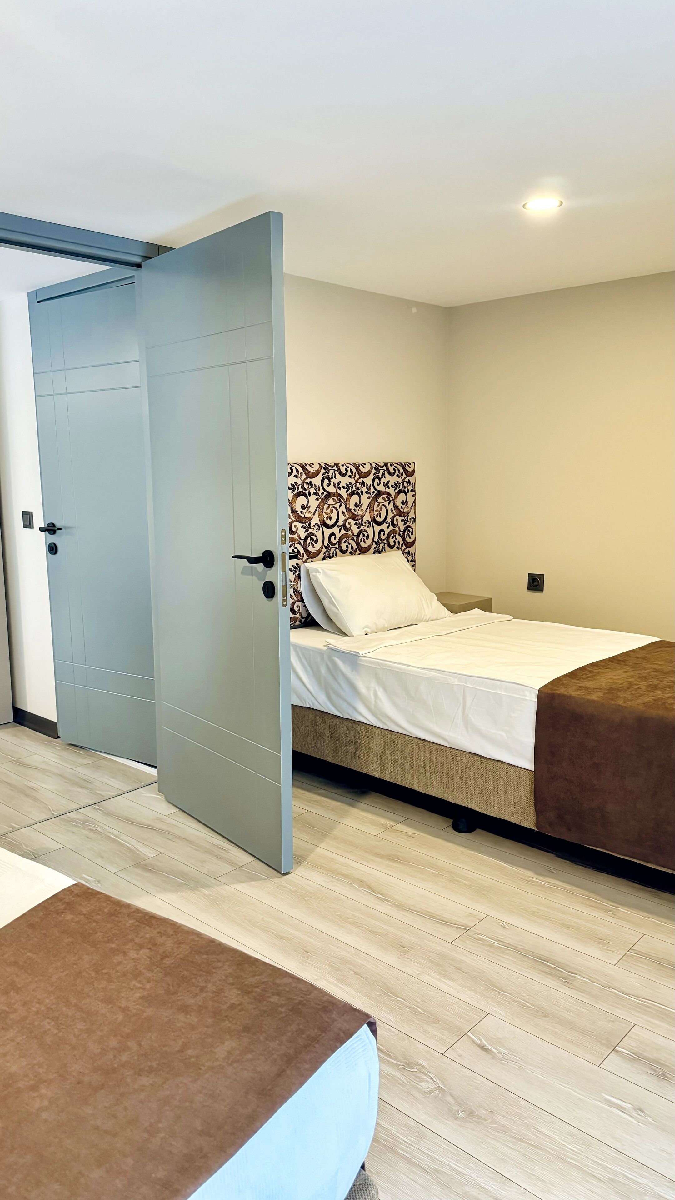 A hotel room with a bed, a wardrobe, and a door.