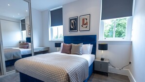 Ein modernes Schlafzimmer mit einem großen Bett, Nachttischen, einem Spiegel und Kunstwerken an der Wand.