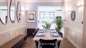 A dining area with a long table set for six, flanked by three mirrors, a framed picture, and a clock on the wall. - Liverpool St Three Bedroom Home Near Tube Station (London)