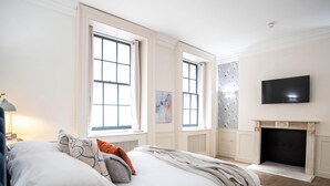 A bedroom with a bed, two windows, a fireplace, and a TV on the wall. - Liverpool St Three Bedroom Home Near Tube Station (London)