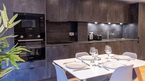 Cozinha moderna com armários escuros, forno Bosch e área de refeições com pratos e copos brancos.