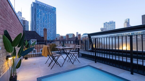 A rooftop pool area with a view of a city skyline, including a tall building and a bridge. - Three Bedroom Near Brick Lane by Belvilla (London)