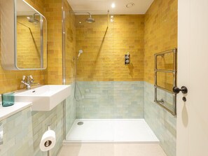 Une salle de bain avec une douche à parois de verre, un lavabo blanc et une porte en verre.