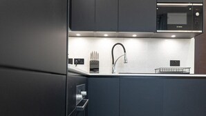 A modern kitchen with a Bosch microwave, a stainless steel faucet, and a dish rack. - Discover Angel Central Two Bedroom by Belvilla (London)