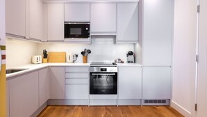 Una cocina moderna con armarios blancos, un microondas Bosch, un tostador y una cafetera.