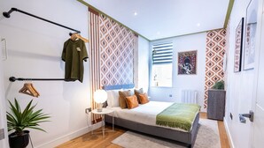 Un dormitorio moderno con cama, mesita de noche, lámpara y perchero.