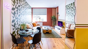 Una sala moderna con una mesa de vidrio, sillas negras, un sofá y un televisor.