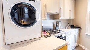 Une cuisine compacte équipée d’un lave-linge intégré, d’une cuisinière et d’un évier.