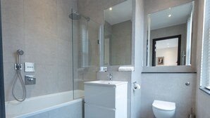 A modern bathroom with a glass-enclosed shower, a white sink, and a toilet. - Culinary Delights 3-bedroom (London)