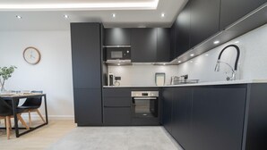 Een moderne keuken met donkere kastjes, een ingebouwde oven en een roestvrijstalen spoelbak.
