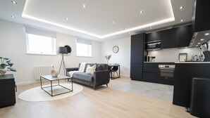 Een moderne woonkamer met een grijze bank, een salontafel en een eethoek.