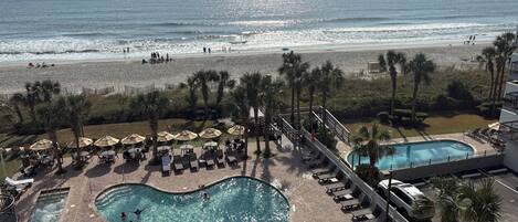 A pool area with a view of the beach and ocean.