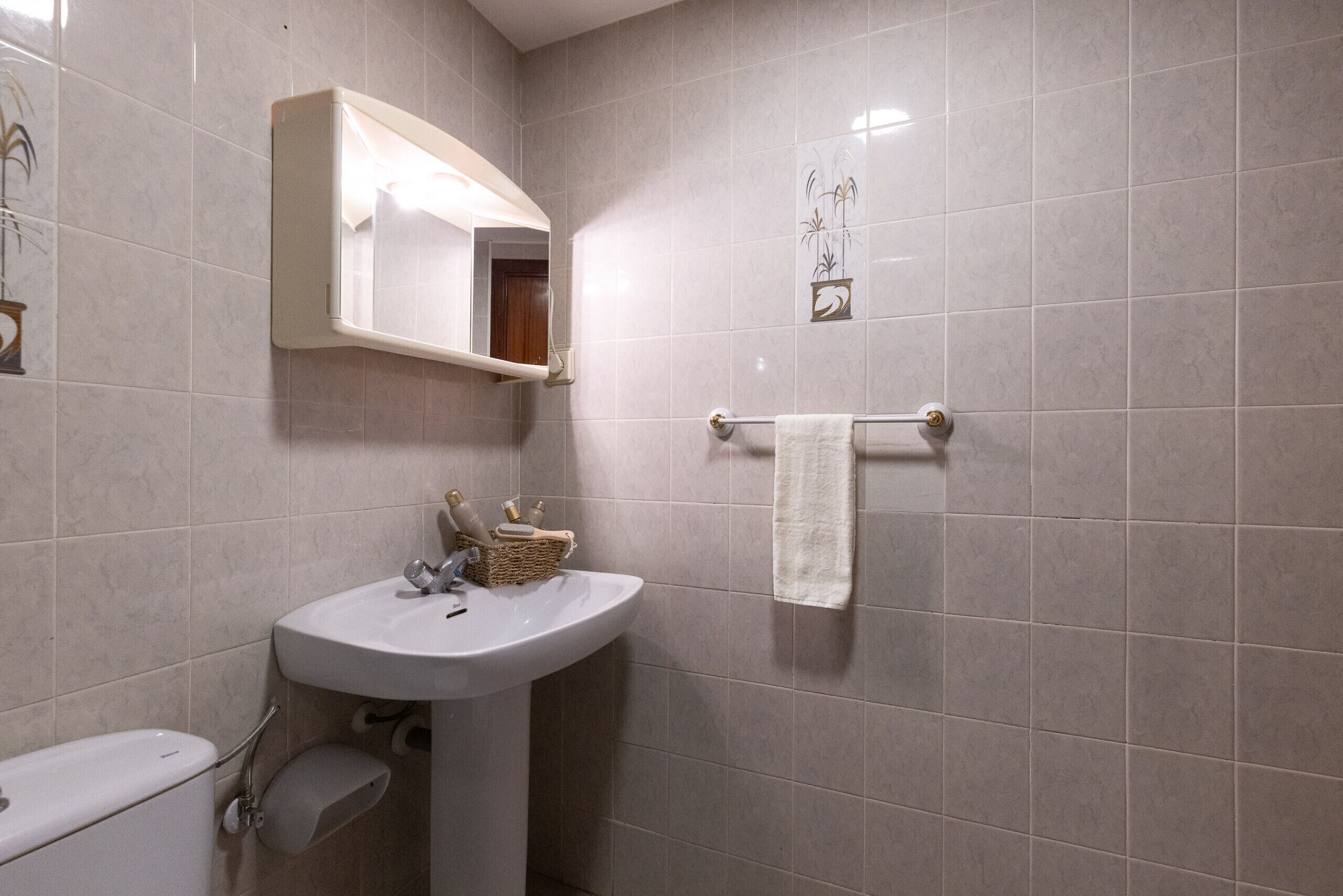 Een badkamer met een wit wastafel, een spiegel, een handdoekhouder en een toilet.