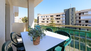 A balcony with a table and chairs, a potted plant, and a view of surrounding buildings. - Cosy Apartment near Beach · AirCon · Pool · UHC PINO ALTO 187 (Salou)