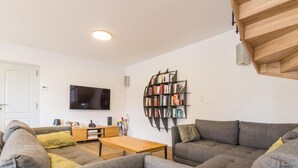 A modern living room with a flat-screen TV, a wooden coffee table, and a bookshelf. - Spacious 5-bedroom countryside house, pet-friendly, parking, internet included, near Mont St-Michel (Saint-Laurent-de-Terregatte)