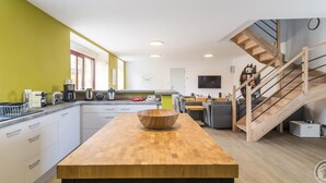 A modern kitchen with a wooden table, a large bowl, and a staircase leading to a loft area. - Spacious 5-bedroom countryside house, pet-friendly, parking, internet included, near Mont St-Michel (Saint-Laurent-de-Terregatte)