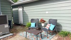 An outdoor patio with two wicker chairs, a small table, and a potted plant.