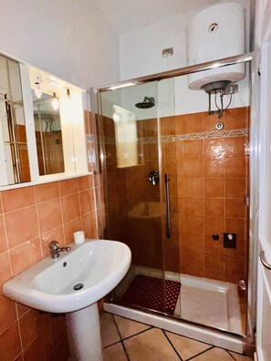 A bathroom with a glass-enclosed shower, a sink, and a toilet. - Le Querce 5 DX (San Teodoro)