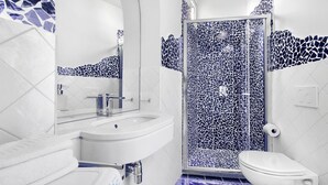 A bathroom with a white sink, a mirror, a toilet, and a shower with mosaic tile walls. - BlueVista Home -Terrace Jacuzzi/Hot Tub (Positano)