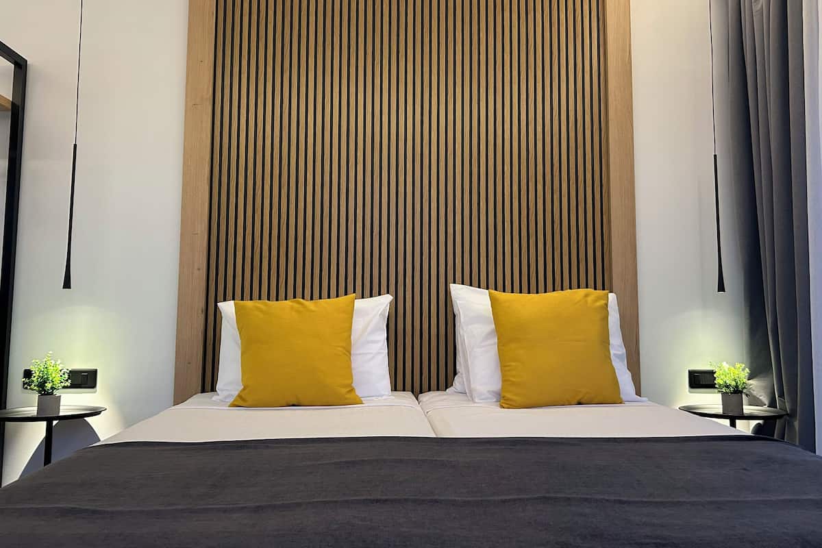A modern bedroom with a large bed, two bedside tables, and a vertical wooden panel wall.