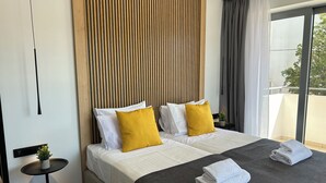 Una habitación de hotel moderna con una cama grande, una mesita auxiliar y vistas al exterior.