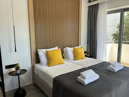Una habitación de hotel moderna con una cama grande, una mesita auxiliar y vistas al exterior.