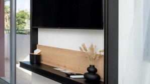 Una sala moderna con un televisor de pantalla plana grande montado en un marco negro.