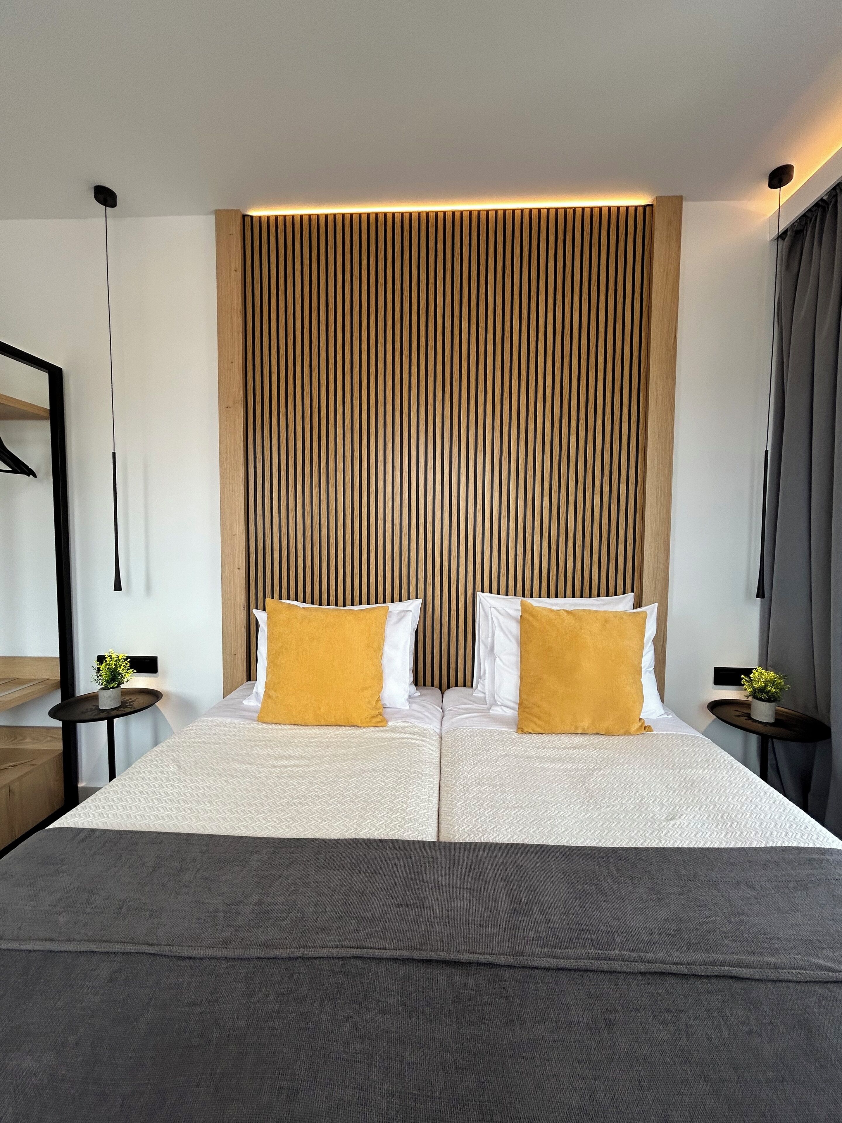 A modern hotel room with a large bed, two bedside tables, and a wooden slat wall design.