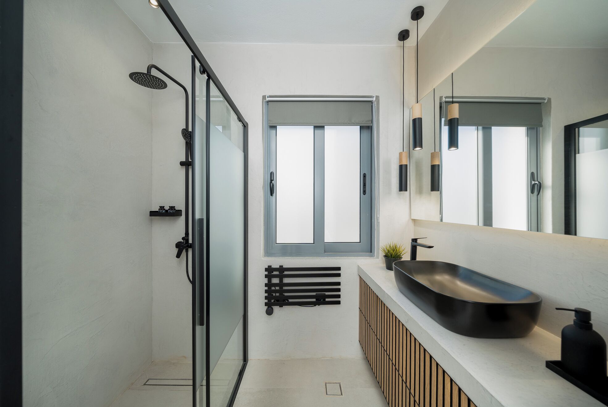 Un baño moderno con cabina de ducha de vidrio, un espejo grande y un lavabo sobre encimera.