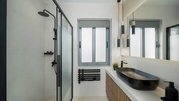 Un baño moderno con cabina de ducha de vidrio, un espejo grande y un lavabo sobre encimera.