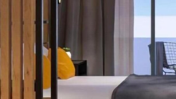 Un dormitorio moderno con una cama grande, cortinas oscuras y vista al cielo.