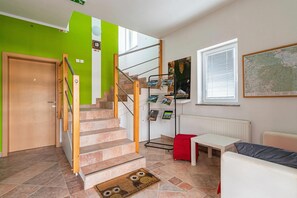 A staircase with a wooden handrail, a red cushion, a white table, and a map on the wall. - Apartments Lavrič (Bloke)