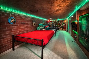 Una habitación con pared de ladrillo, una cama roja, un peluche de tortuga y un cartel de Tortugas Ninja.
