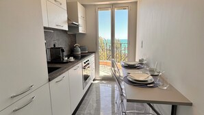 Et moderne køkken med hvide skabe, en marmorgulv og et spiseområde med havudsigt.