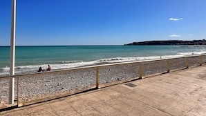 En strand med en belagt sti og gelænder.