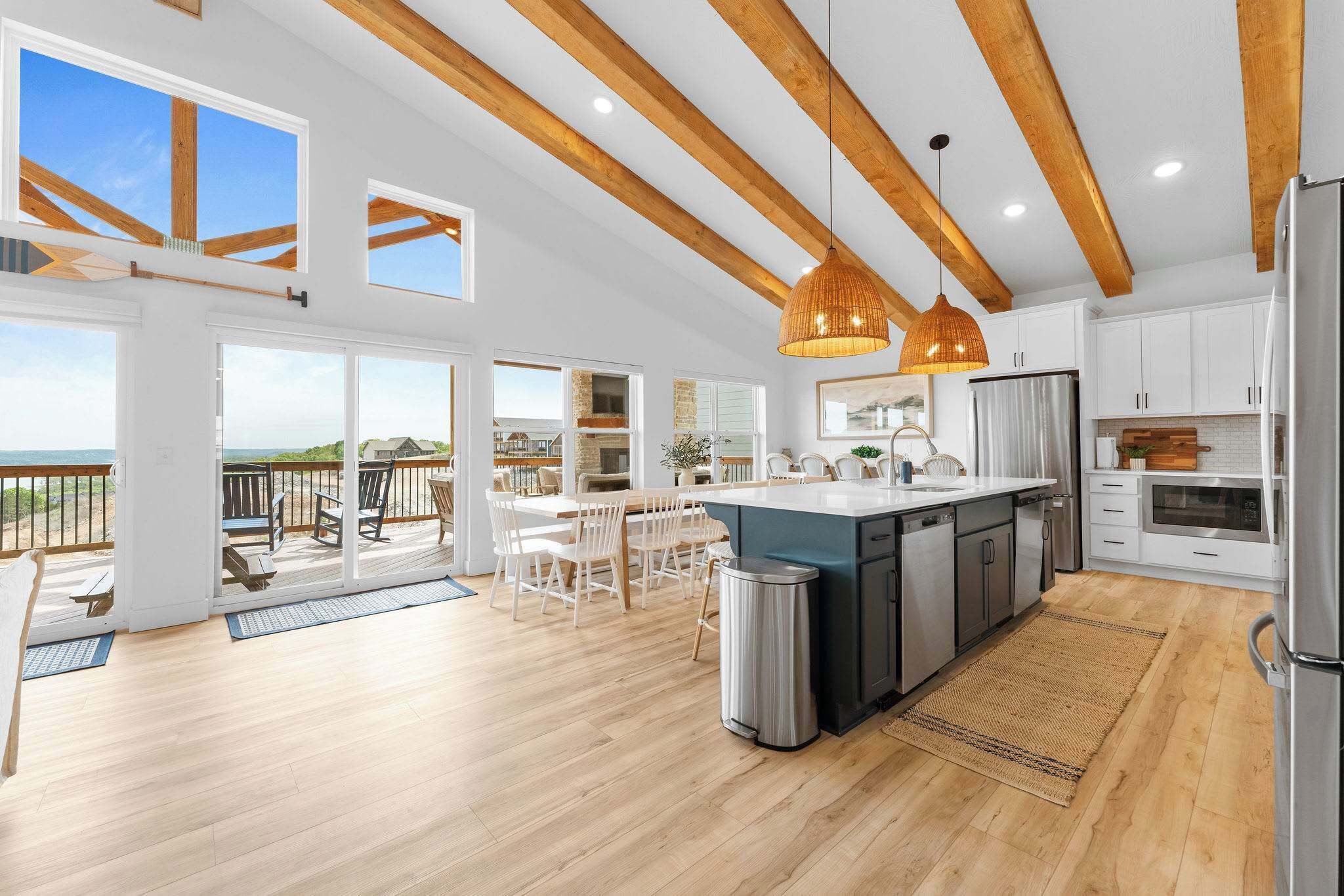 A spacious kitchen with wooden beams, a large island, and a view to the outside.