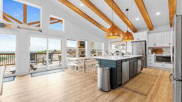 A spacious kitchen with wooden beams, a large island, and a view to the outside.